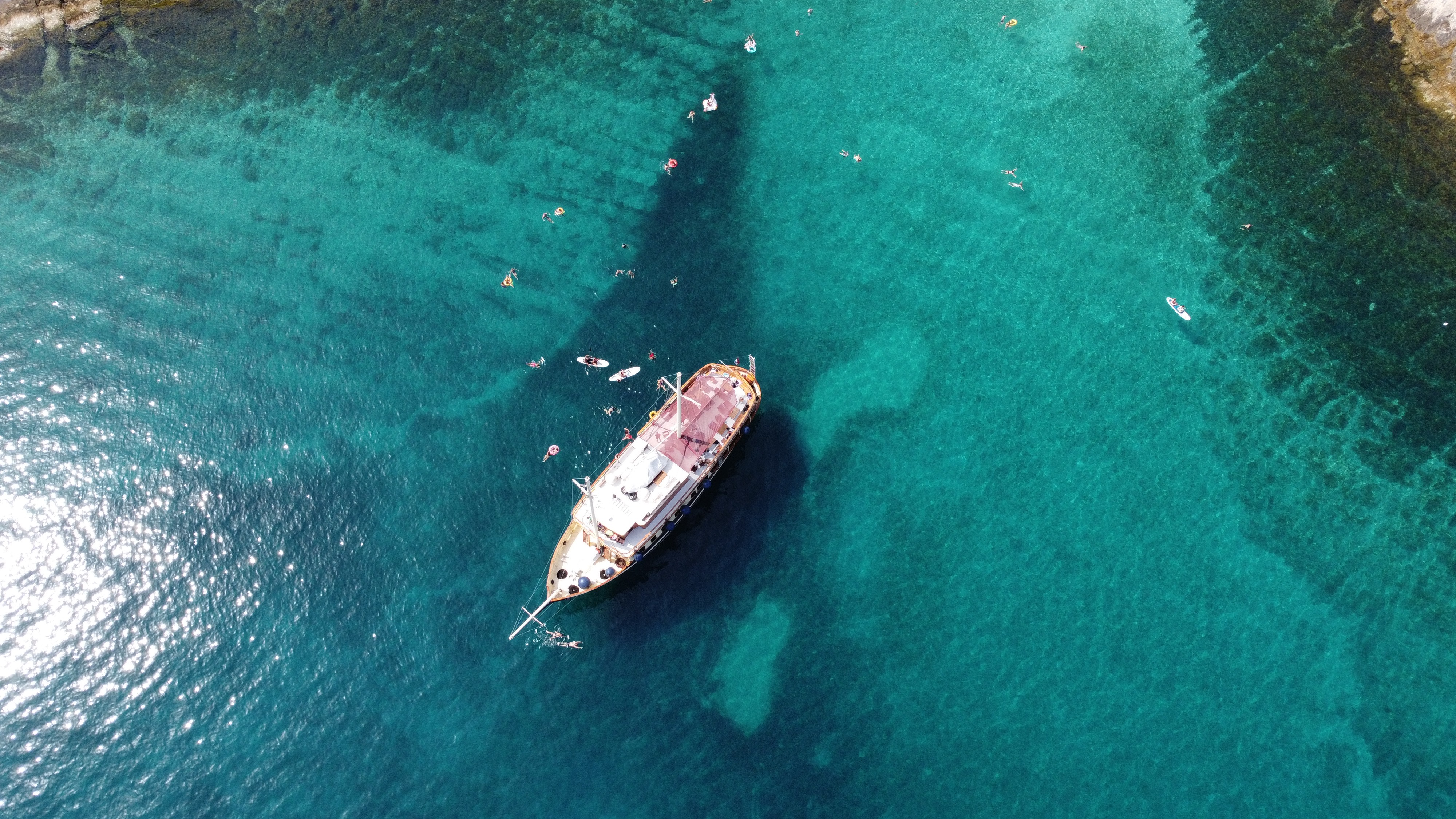 Overhead view of Polaris in crystal-clear water with guests swimming, snorkelling and paddleboarding