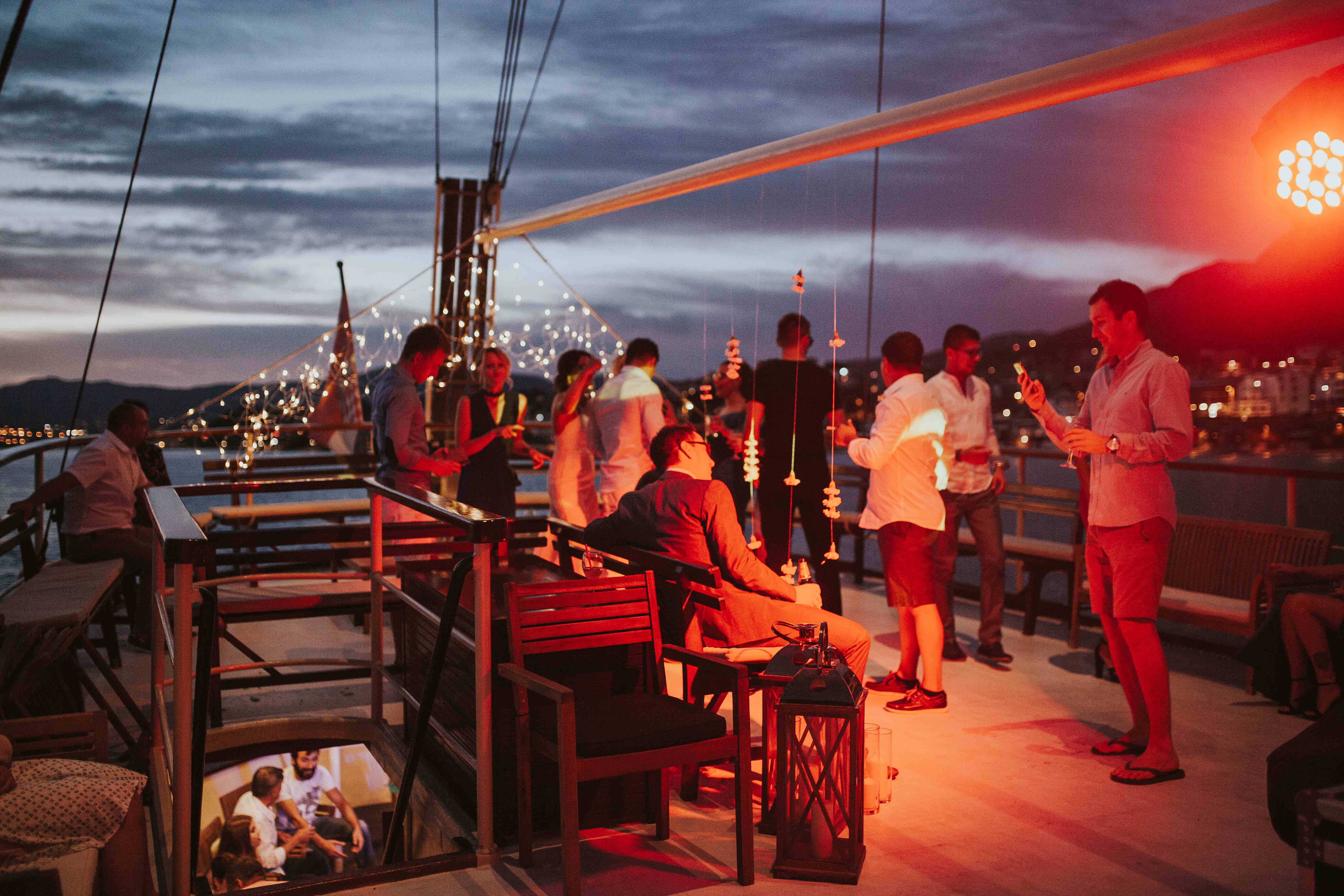 Gäste mit Drinks auf dem Deck der Polaris unter Lichterketten in der Abenddämmerung