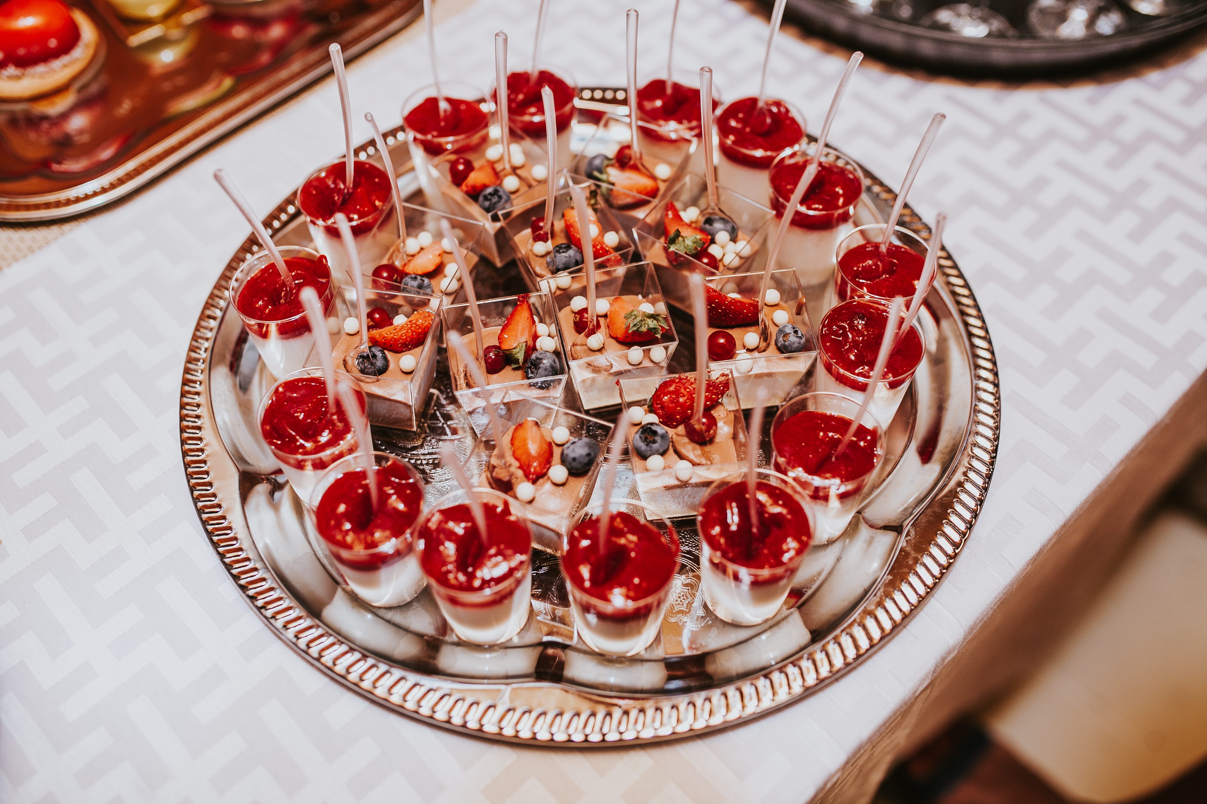 Silver tray of dessert verrines topped with fresh berries and white chocolate pearls