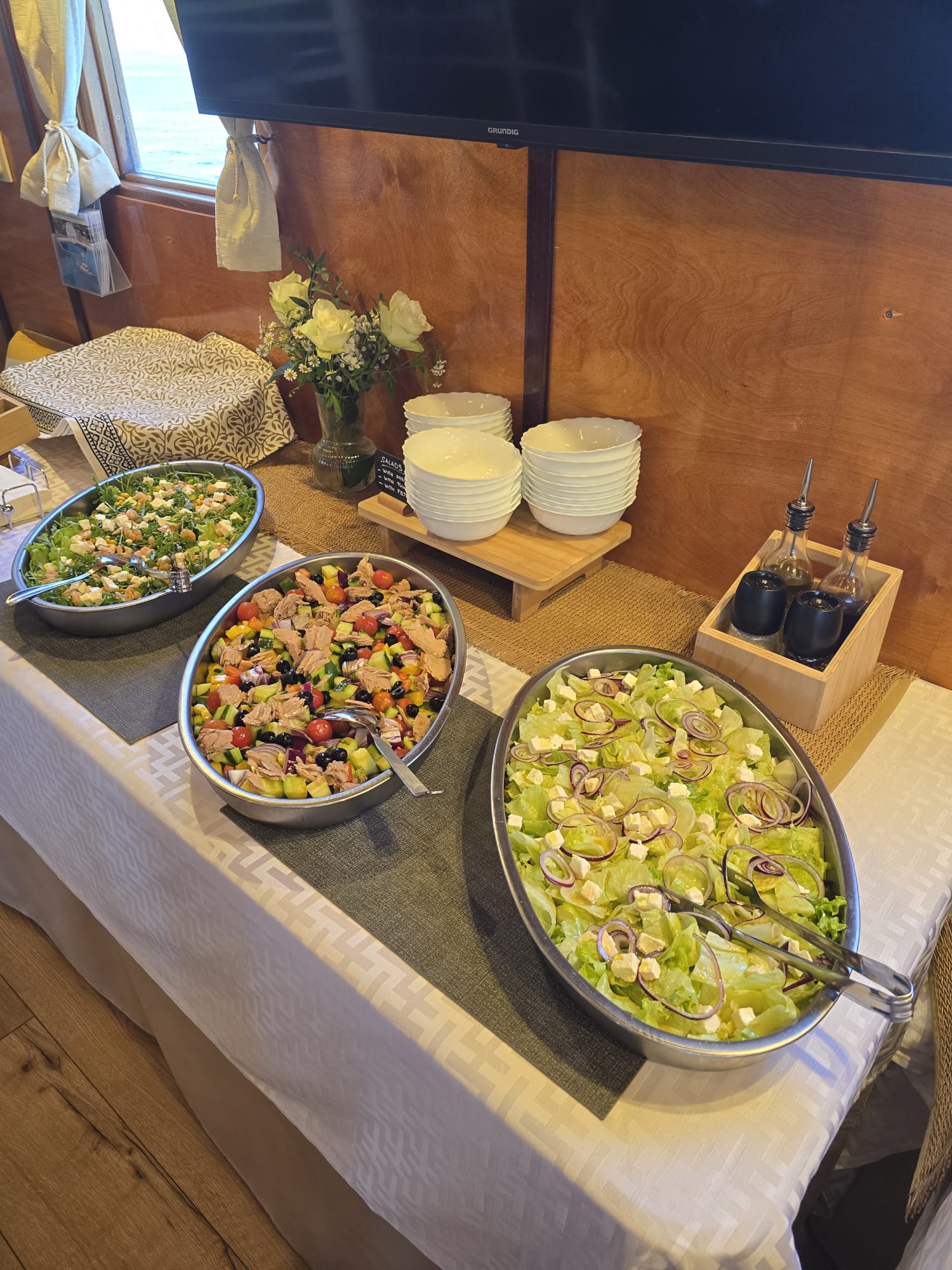 Three bowls of fresh salads — arugula, tuna and iceberg with feta and red onion