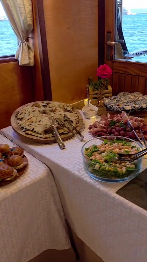 Onboard buffet of soparnik, charcuterie and fresh salad set beside the cabin windows with the Adriatic behind
