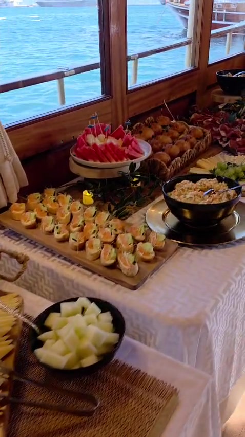 Spread of salmon canapés, fresh watermelon and warm pastries laid out along the window with sea views