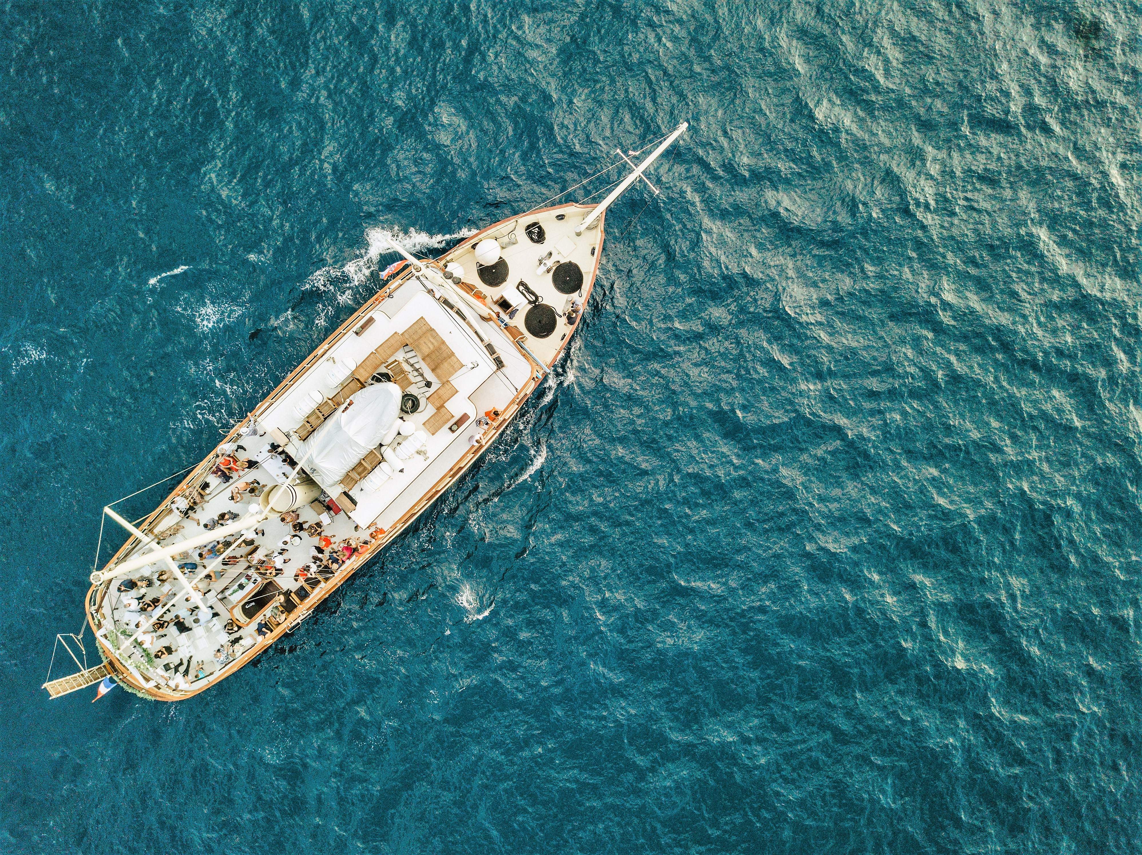 Aerial drone view of the yacht Polaris sailing the deep-blue Adriatic with guests gathered on the open deck