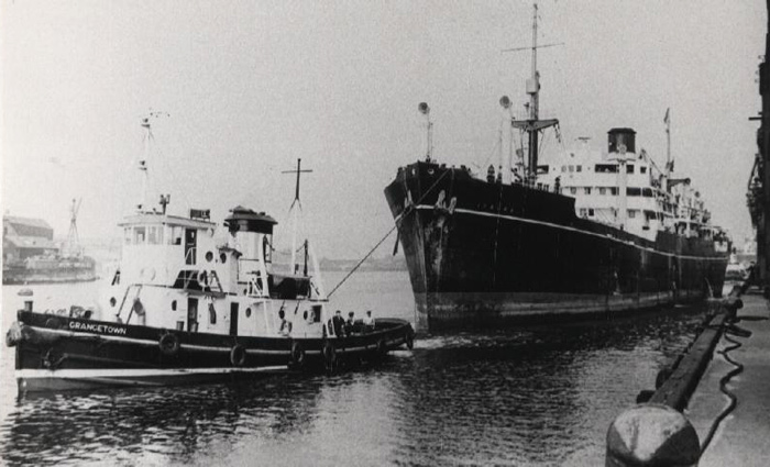 The tug Grangetown working alongside a large ocean-going cargo ship in harbour