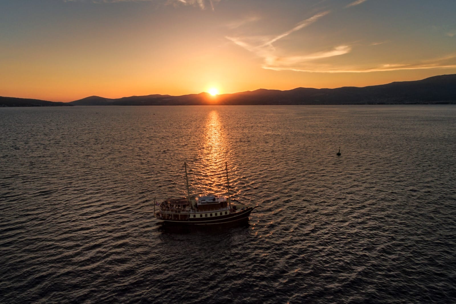 Aerial view of Polaris anchored as the sun sets and reflects on the water