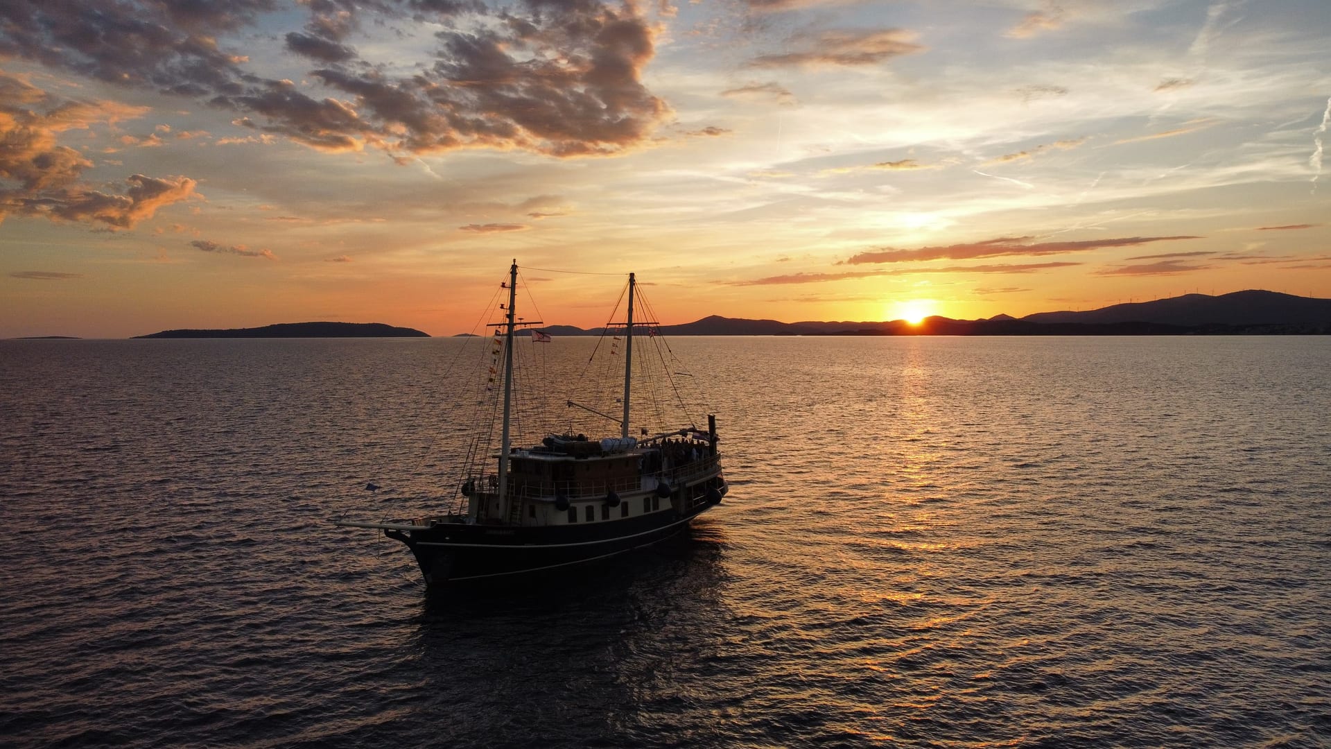 Aerial view of Polaris sailing under a dramatic sunset sky