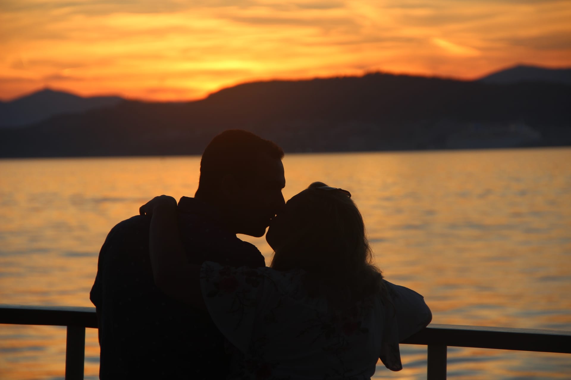 A couple kissing, silhouetted against the orange sunset