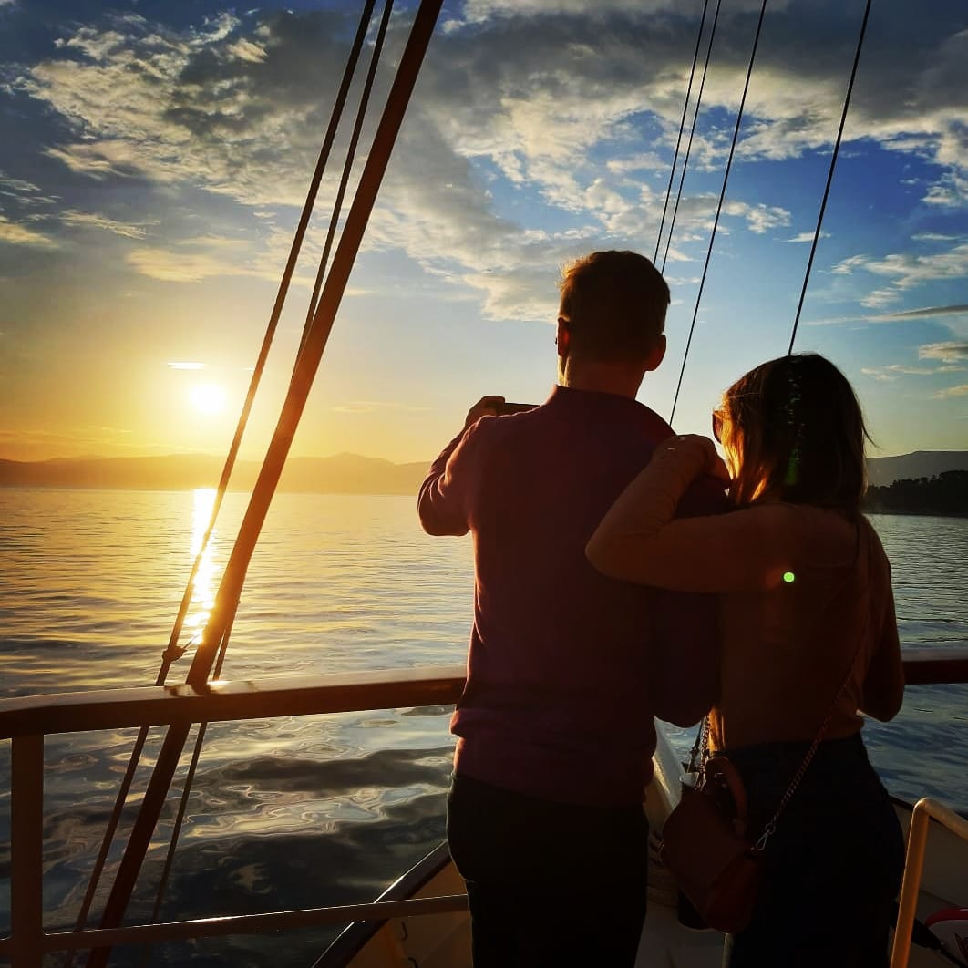 A couple embracing at the rail as the sun sets over the Adriatic
