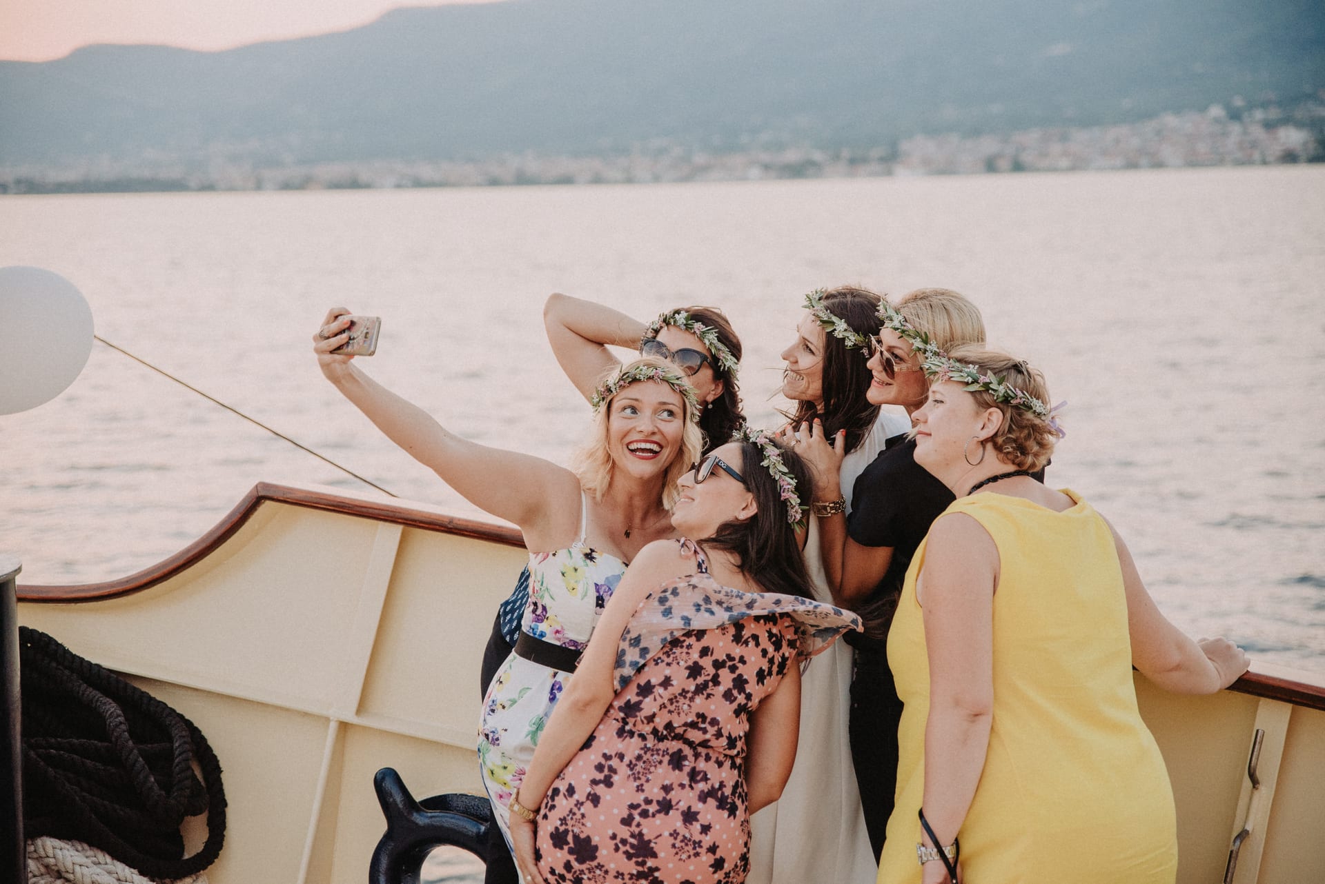 Group of friends in flower crowns taking a selfie at sunset
