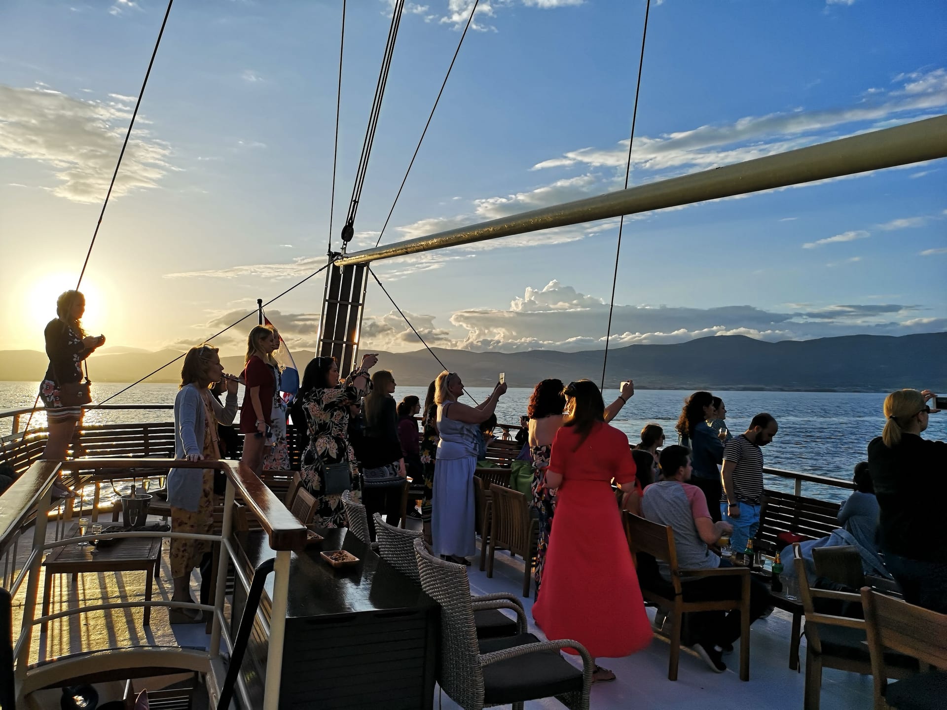 Guests on the upper deck photographing the sunset in golden light