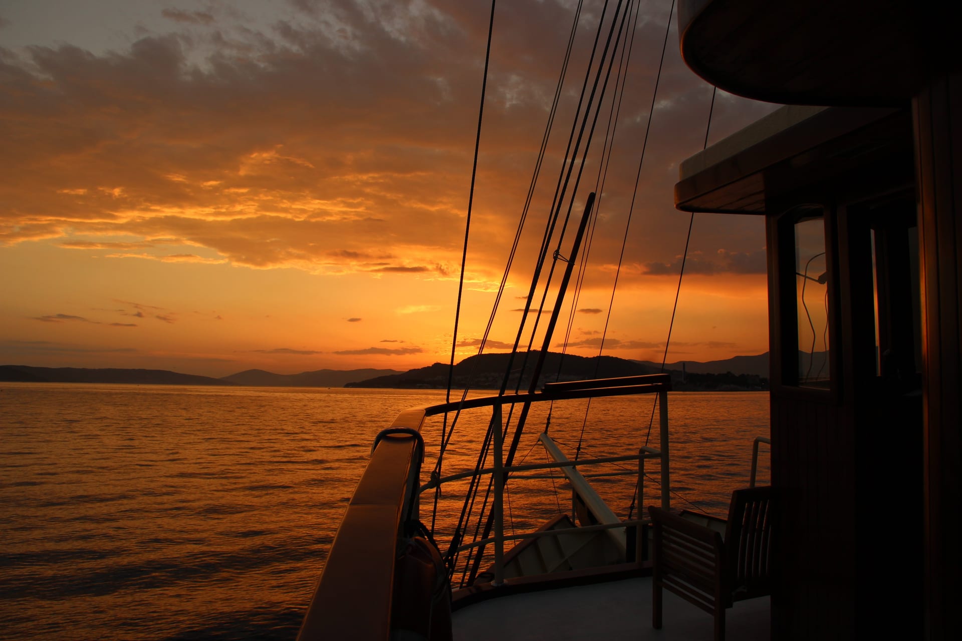Deck and rigging of Polaris silhouetted against a dramatic orange sky