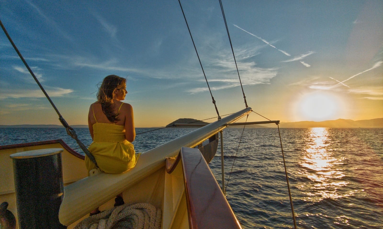 Guest in a yellow dress on the bowsprit of Polaris watching the sun set