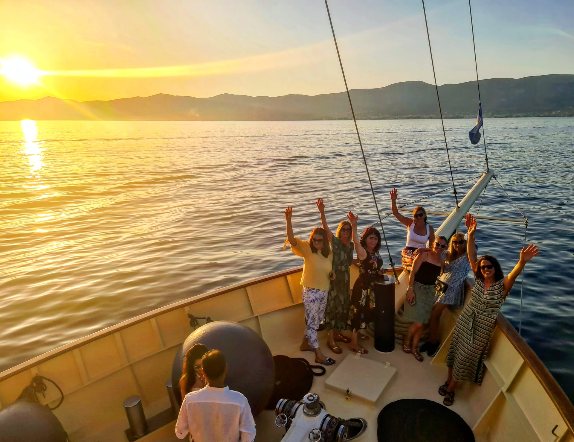 Group of women waving from the bow of Polaris in warm sunset light
