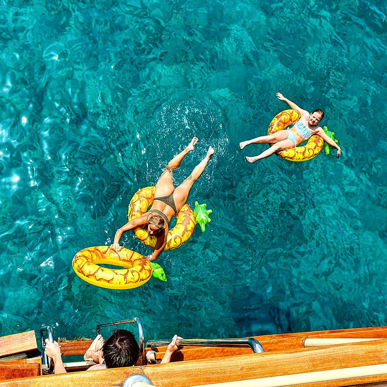Guests relaxing on pineapple floats in clear water