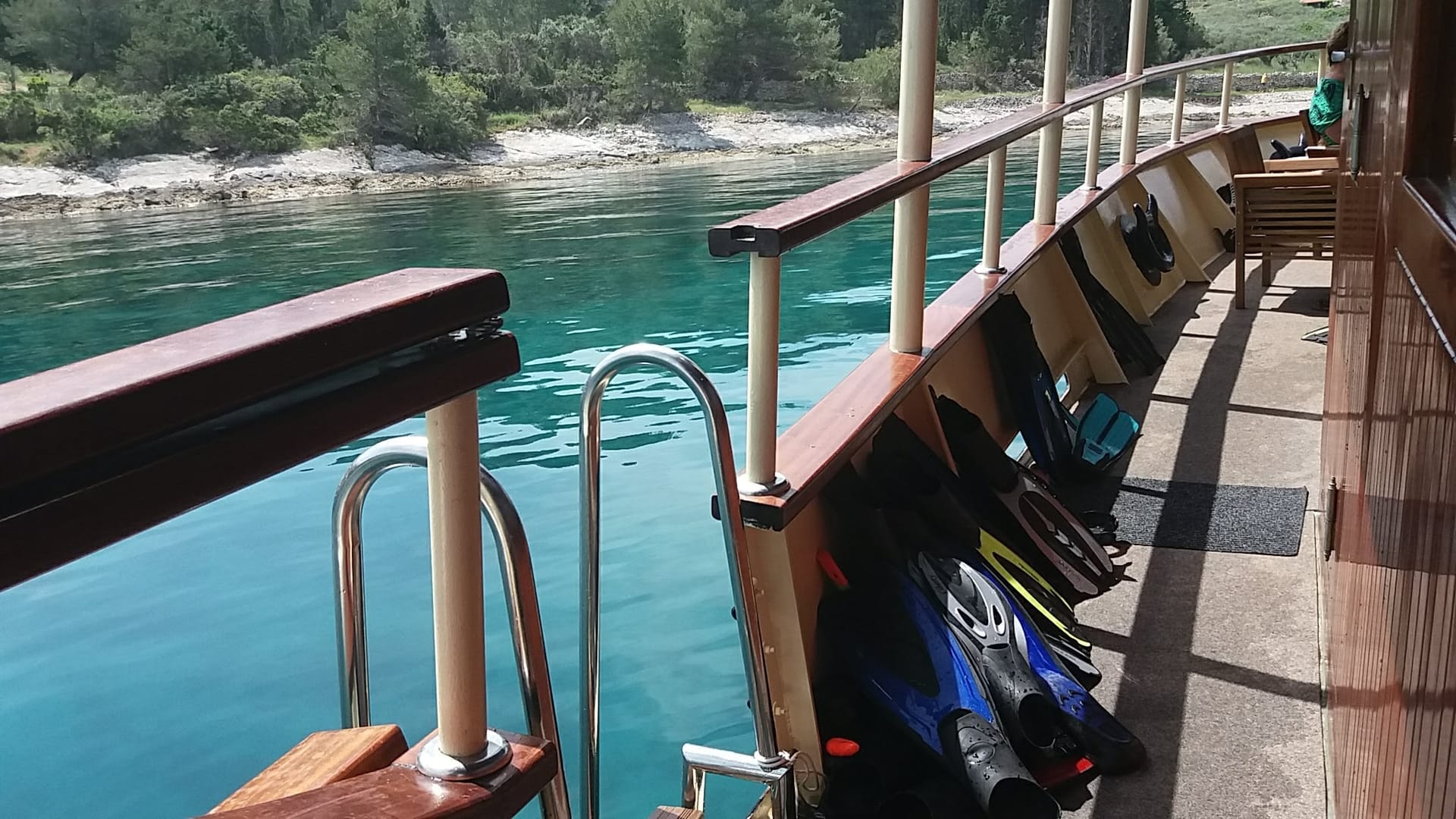 Snorkelling gear and swim ladder along the deck beside clear water