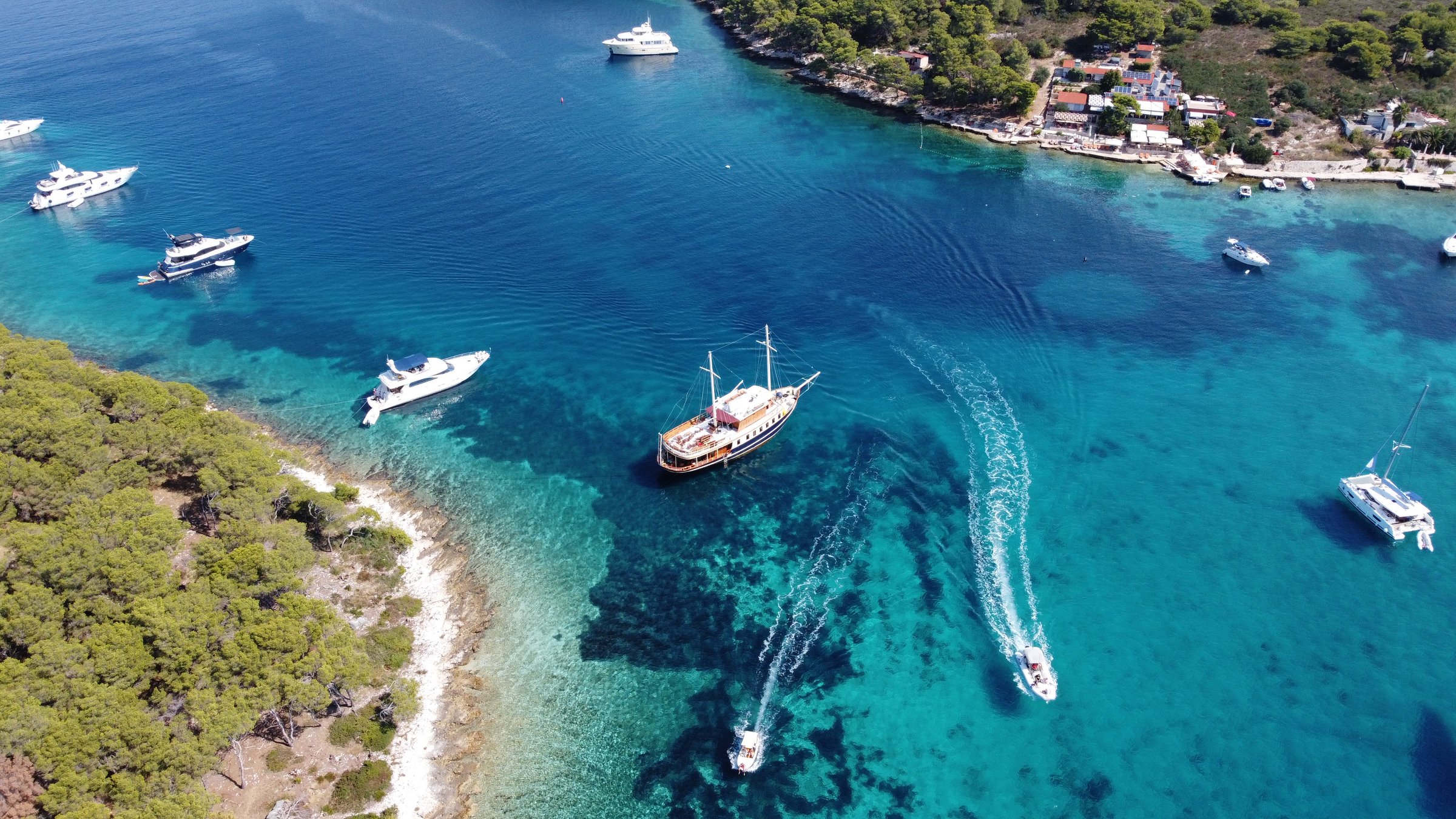 Luftaufnahme der Yacht Polaris vor Anker zwischen Booten in einer türkisfarbenen Adriabucht bei Split